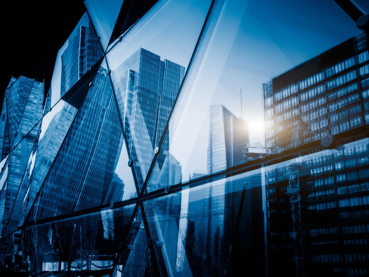 View of a modern glass skyscraper reflecting the buildings around,blue toned image